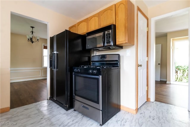 kitchen with black appliances, a chandelier, and baseboards