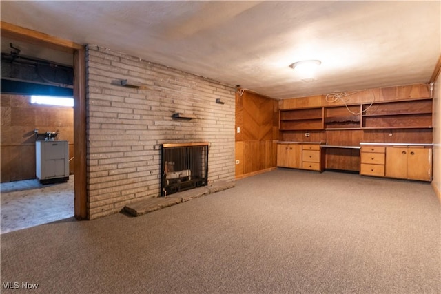 unfurnished living room featuring light colored carpet, a fireplace, and wooden walls