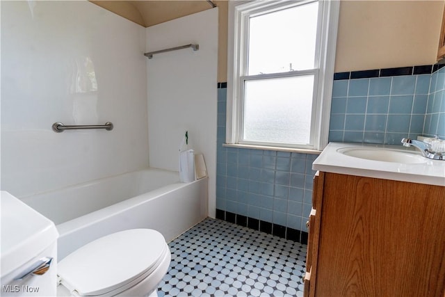 bathroom featuring tile walls, toilet, vanity, tile patterned flooring, and a wainscoted wall
