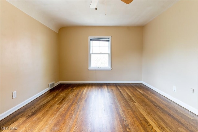 spare room with wood finished floors, a ceiling fan, and baseboards