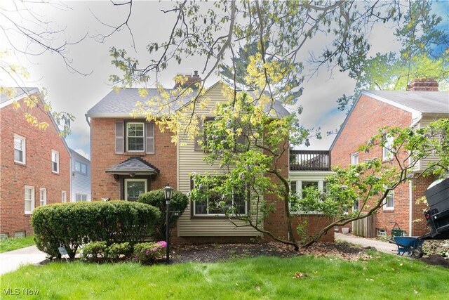 view of front of house featuring a chimney, brick siding, and a front lawn