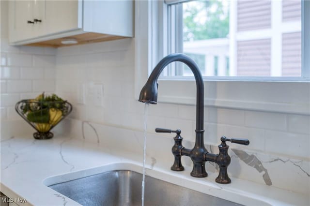 2332 Allison Rd, University Heights, OH 44118 - kitchen view of a sink, decorative backsplash, white cabinets, and light stone counters