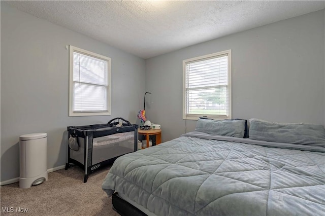 bedroom featuring carpet flooring, multiple windows, a textured ceiling, and baseboards