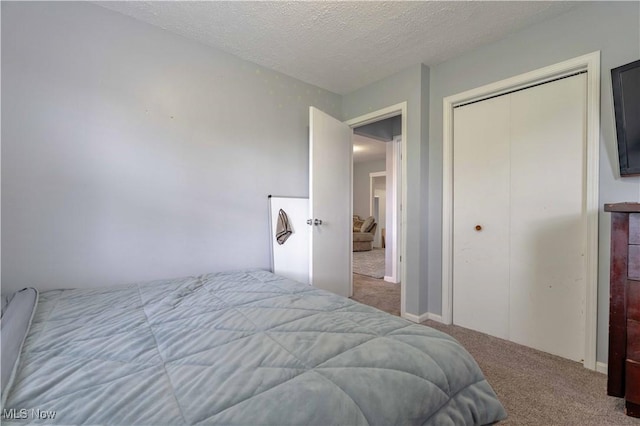 bedroom with carpet, a textured ceiling, and a closet