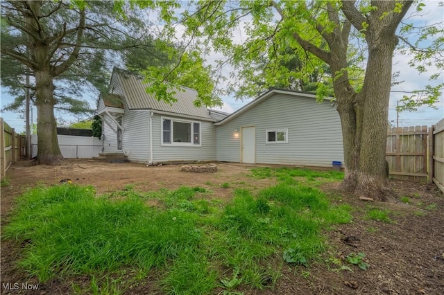 rear view of property featuring a fenced backyard and metal roof