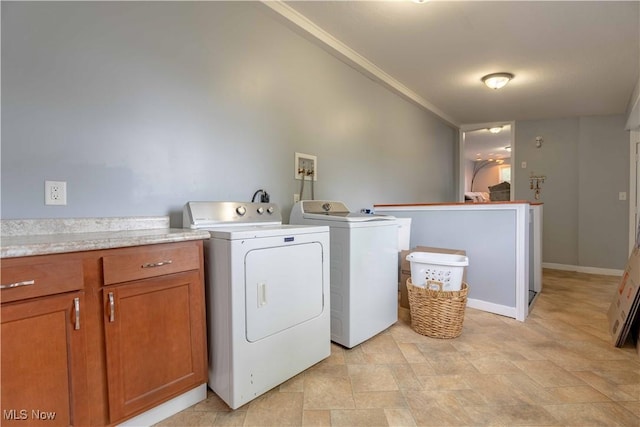 washroom featuring washing machine and clothes dryer, stone finish floors, cabinet space, and baseboards