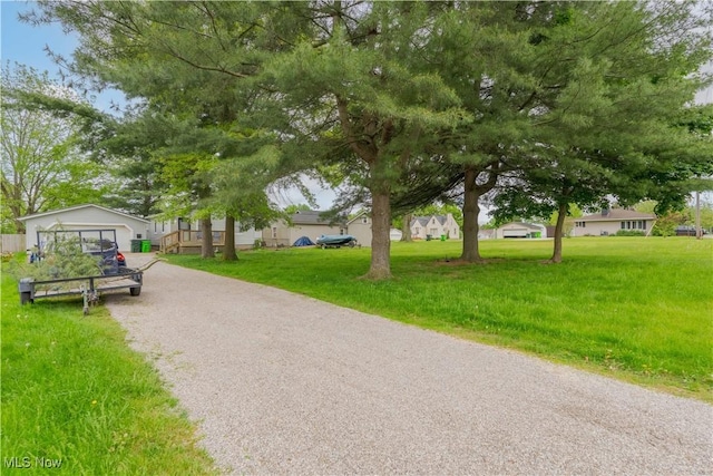 view of home's community with gravel driveway and a yard