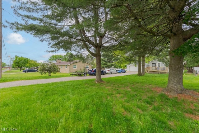 view of grassy yard featuring driveway and a garage