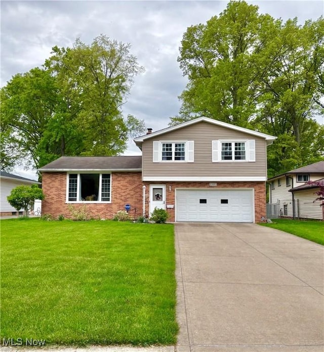 tri-level home with an attached garage, driveway, a front lawn, and brick siding