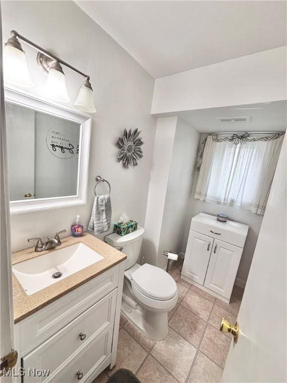 half bathroom with toilet, vanity, and tile patterned floors