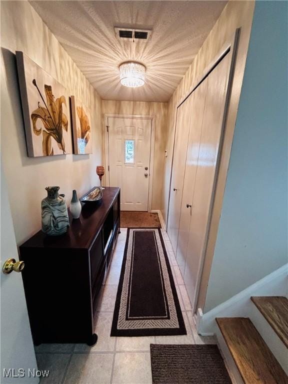 entryway with a chandelier, light tile patterned floors, and stairway