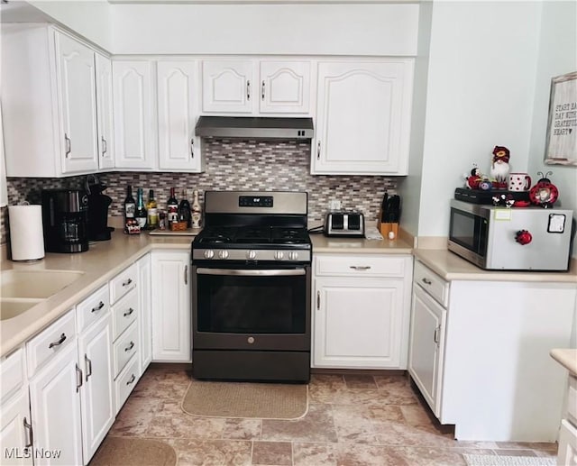 kitchen with stainless steel appliances, under cabinet range hood, white cabinets, and decorative backsplash
