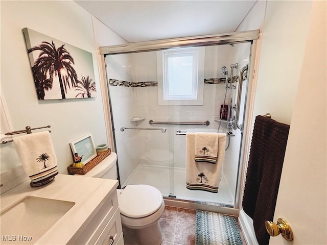 bathroom featuring toilet, a stall shower, tile patterned floors, and vanity