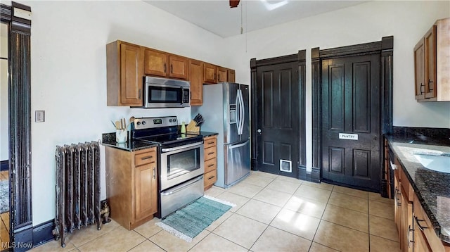 2963 Scranton Rd, Cleveland, OH 44113 - kitchen with stainless steel appliances, radiator, dark stone counters, and brown cabinets