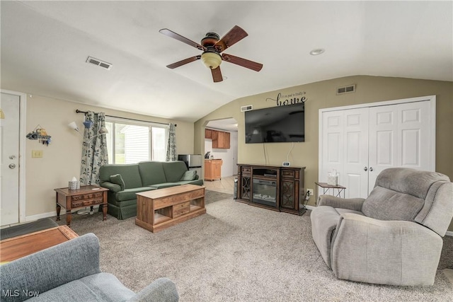 living area with lofted ceiling, ceiling fan, carpet, a fireplace, and arched walkways