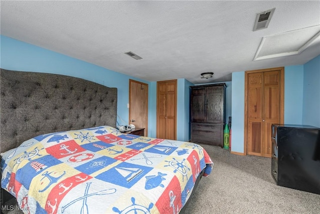 bedroom with attic access, light colored carpet, and a textured ceiling
