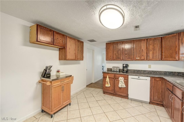 kitchen with dishwasher, dark countertops, brown cabinets, baseboards, and a textured ceiling