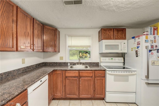 kitchen with white appliances, a sink, dark countertops, brown cabinetry, and a textured ceiling