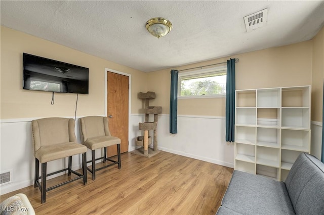 living area with a textured ceiling, wood finished floors, and baseboards