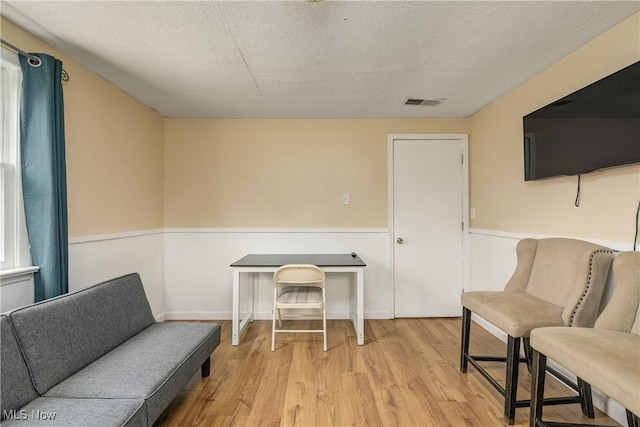 living area with wood finished floors, a wainscoted wall, and a textured ceiling
