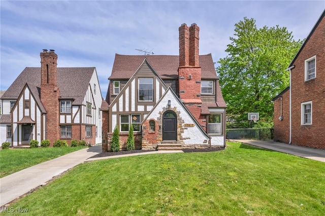 17617 Lomond Blvd, Shaker Heights, OH 44120 - tudor home featuring a chimney, a front yard, and roof with shingles