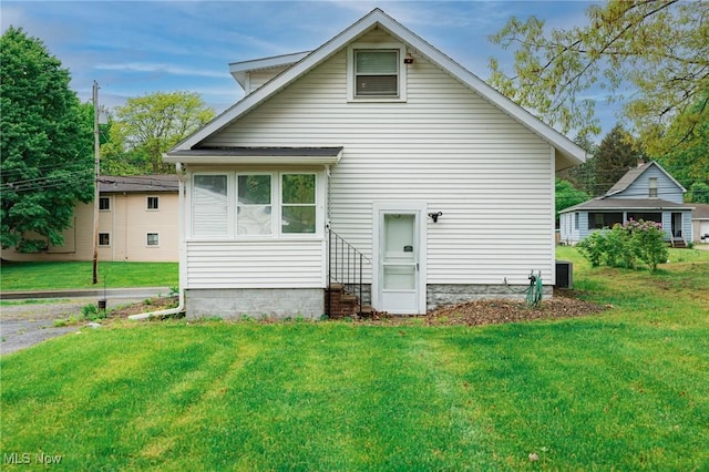 rear view of property featuring entry steps and a yard