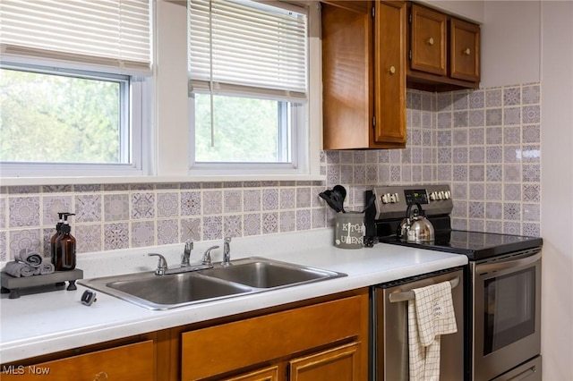 kitchen featuring stainless steel appliances, brown cabinetry, a sink, and decorative backsplash