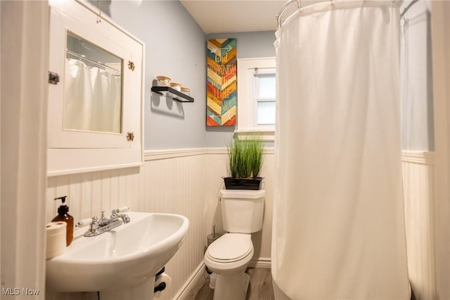 full bath featuring wainscoting, a sink, toilet, wood finished floors, and a shower with curtain