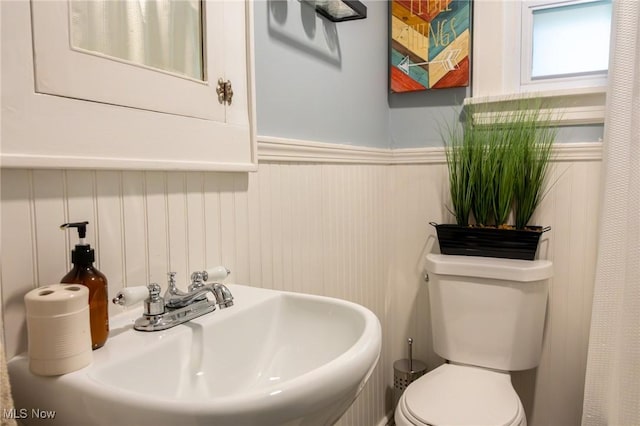 bathroom with a sink, a wainscoted wall, and toilet