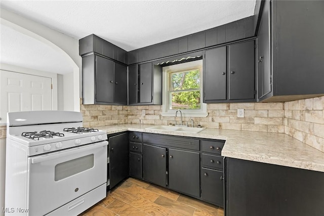 1254 Delos St, Akron, OH 44306 - kitchen featuring white gas range oven, a sink, tasteful backsplash, and light countertops