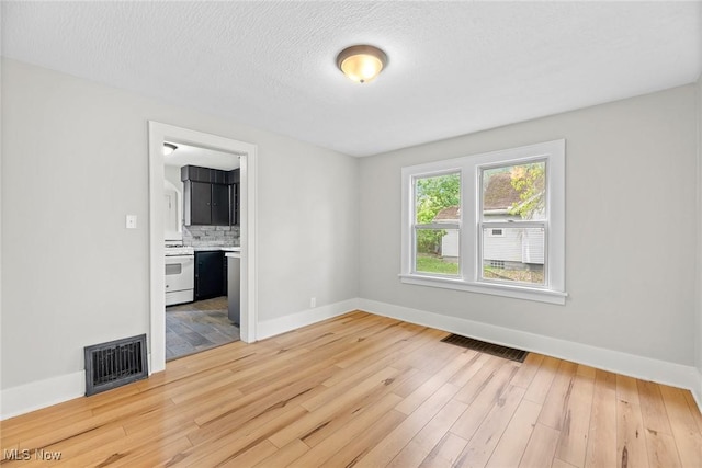 1254 Delos St, Akron, OH 44306 - unfurnished room with light wood finished floors, baseboards, and a textured ceiling