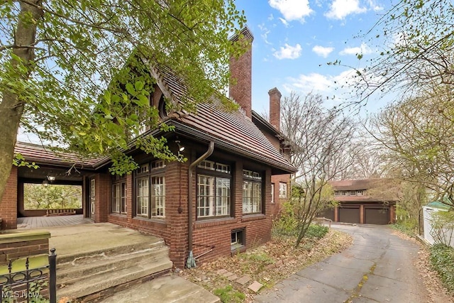 245 Merriman Rd, Akron, OH 44303 - view of home's exterior with a chimney, brick siding, a porch, and an outbuilding