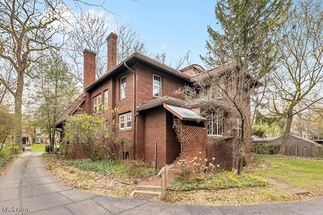 245 Merriman Rd, Akron, OH 44303 - view of home's exterior with a chimney, brick siding, and fence
