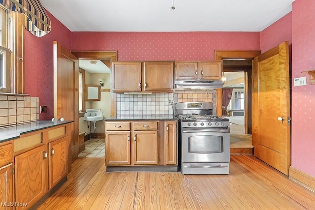 245 Merriman Rd, Akron, OH 44303 - kitchen featuring stainless steel range with gas stovetop, light wood-style floors, wallpapered walls, range hood, and tasteful backsplash