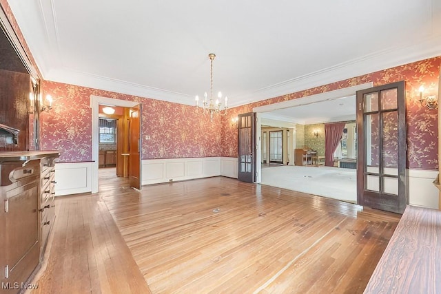 245 Merriman Rd, Akron, OH 44303 - unfurnished dining area featuring wallpapered walls, a chandelier, a wainscoted wall, hardwood / wood-style floors, and french doors