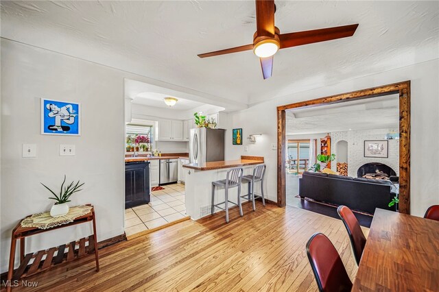 living room featuring a ceiling fan, light wood-style floors, and baseboards
