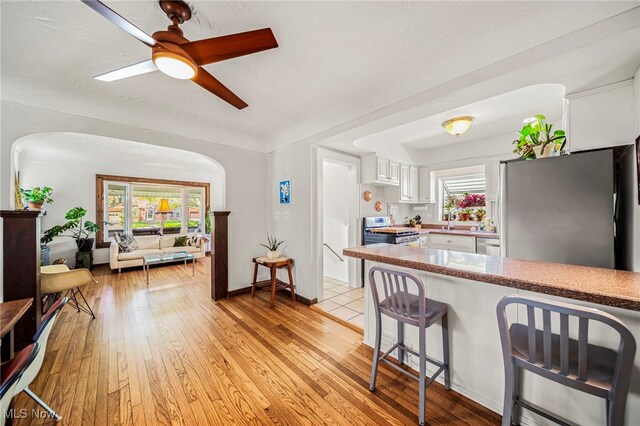 kitchen with stainless steel appliances, white cabinets, a breakfast bar, and light wood-style flooring