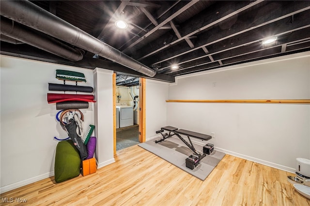 exercise room featuring wood finished floors, baseboards, and washer and dryer