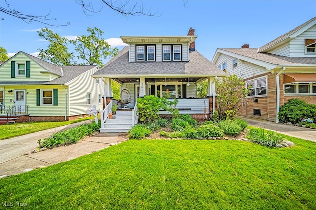 bungalow-style house with covered porch, a front lawn, and roof with shingles