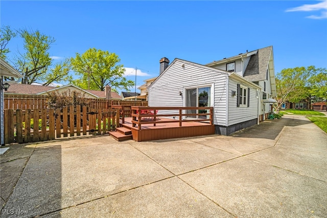 back of property with fence, a deck, and roof with shingles