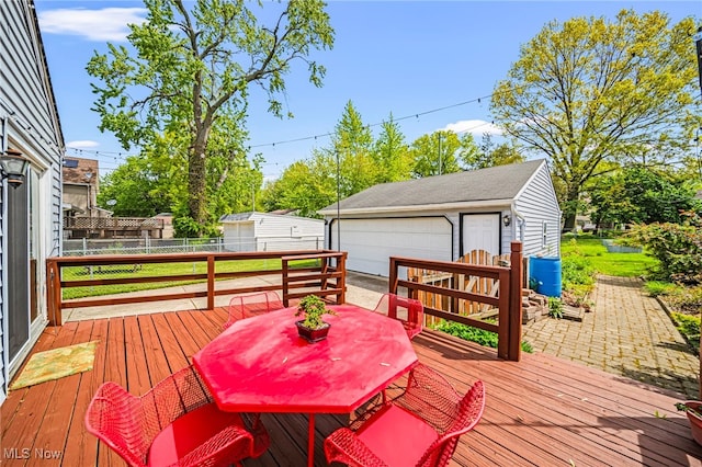 deck featuring a detached garage, an outbuilding, fence, and outdoor dining area