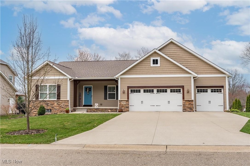 7273 Ashmoore Ave NW, North Canton, OH 44720 - craftsman inspired home featuring a garage, a front yard, driveway, and stone siding