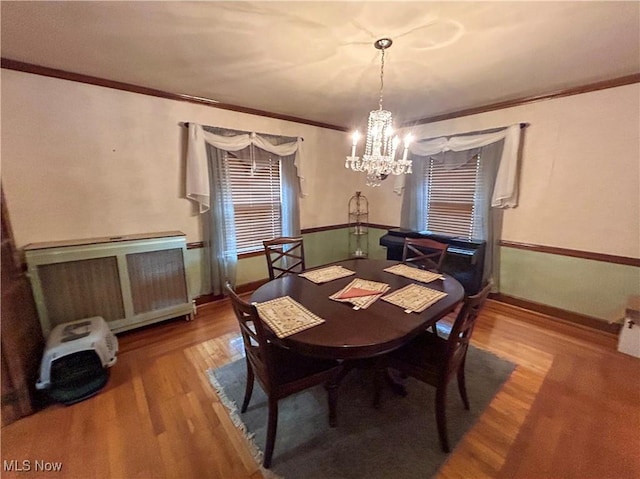 553 Willard Ave SE, Warren, OH 44483 - dining area with radiator heating unit, wood finished floors, a chandelier, and ornamental molding