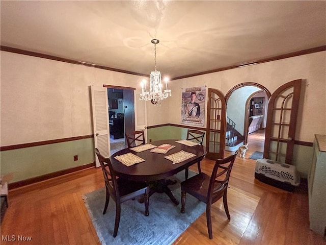 553 Willard Ave SE, Warren, OH 44483 - dining room with wood-type flooring, a chandelier, arched walkways, and ornamental molding