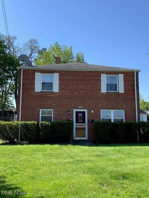 view of front of home featuring a front lawn, brick siding, and a chimney