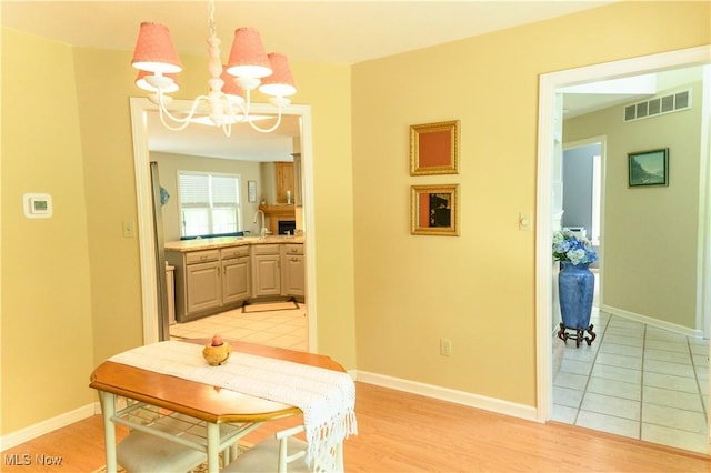 dining space featuring a chandelier, baseboards, and light wood-type flooring