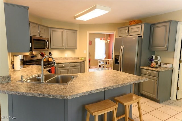 kitchen with stainless steel appliances, gray cabinets, a peninsula, and a kitchen breakfast bar
