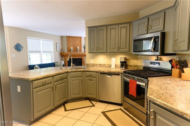 kitchen with appliances with stainless steel finishes, a sink, a peninsula, gray cabinetry, and light tile patterned floors