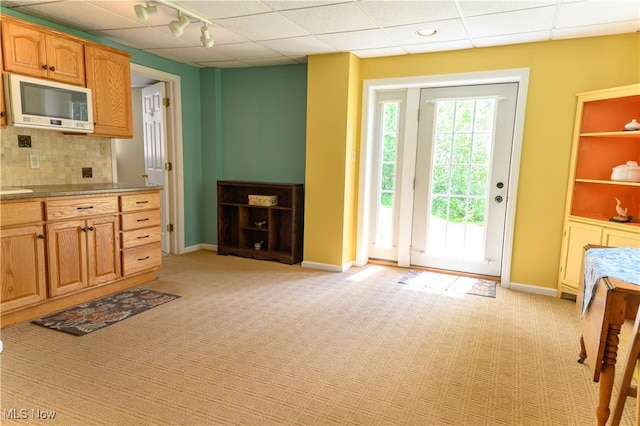 kitchen featuring white microwave, light carpet, tasteful backsplash, baseboards, and a paneled ceiling