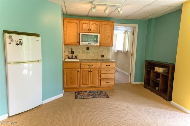 kitchen with white appliances, decorative backsplash, light colored carpet, and rail lighting